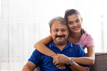 Indian father and girl spending good time while sitting on sofa