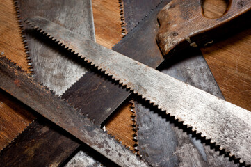Old vintage metal saws for wood of different shapes and sizes, crumpled on a wooden background.