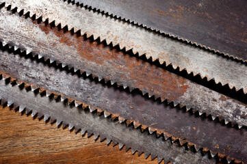 Old vintage metal saws for wood of different shapes and sizes, crumpled on a wooden background.