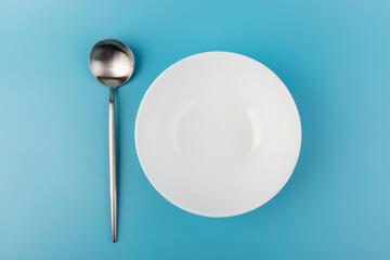 Empty plate with spoon on blue background. Flat lay Dishes for breakfast, lunch or dinner Mock up