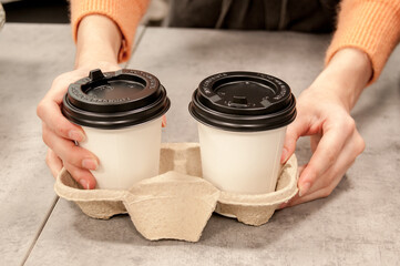 Barista girl serves two takeaway cafes