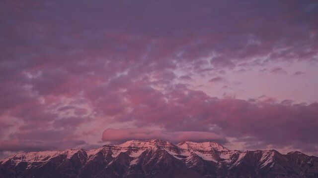 Timelapse of colorful clouds over snow capped mountain in Utah zoomed into the top of Timpanogos.