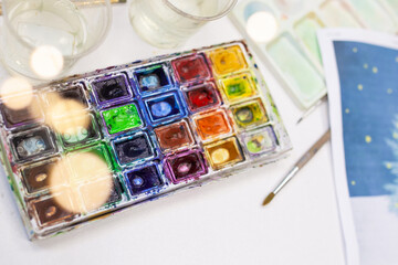 Set of watercolor paints and paintbrushes for painting closeup. Selective focus.