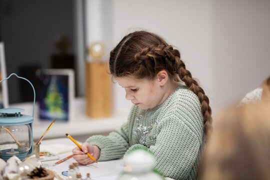 The girl paints with watercolors at the Christmas master class. Education and creativity of children at school. Young artist draws a sketch