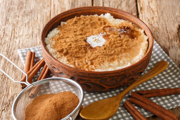 Traditional Danish Rice Pudding risengrod topped with cinnamon, sugar and butter close up in the bowl on the table. Horizontal