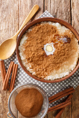 Rice pudding topped with cinnamon, sugar and butter closeup in a bowl on the table. vertical top view from above