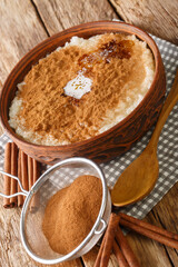 Rice pudding topped with cinnamon, sugar and butter close-up in a bowl on the table. vertical