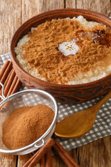 Danish Rice Pudding also known as Risengrod with sugar, butter and cinnamon close up in the bowl on the table. Vertical