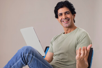 Happy Indian man posing in front of camera while holding tablet