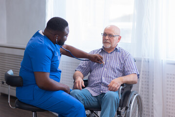 Obraz premium Caregiver and old man in a wheelchair. Professional nurse and patient in a nursing home. Assistance, rehabilitation and health care.