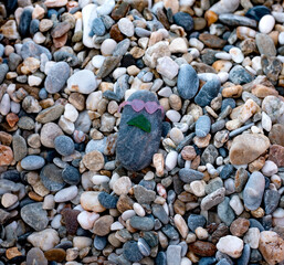 A Pebble stone wearing sunglasses  and mustaches on the pebble beach on summer day. Creativity and playing concept