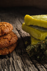 biscuits with marijuana and cannabis butter and bud on an old wooden background close-up. Healthy medical food with cannabis. the buds are inaccurately scattered. rustic. Vertical.
