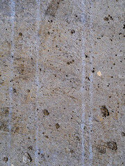 Textured concrete background with many potholes, scratches, irregularities, scuffs with colored traces. Vertical
