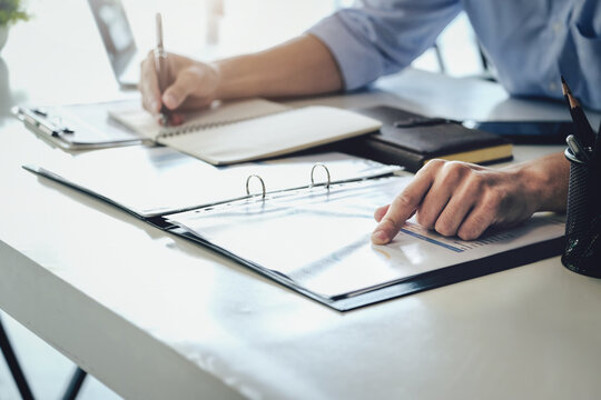 Examining the financial budget, a male auditor is pointing to a file to summarize the company's irregular financial budget.