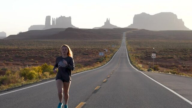 Girl running along a desolate highway in the desert western United States