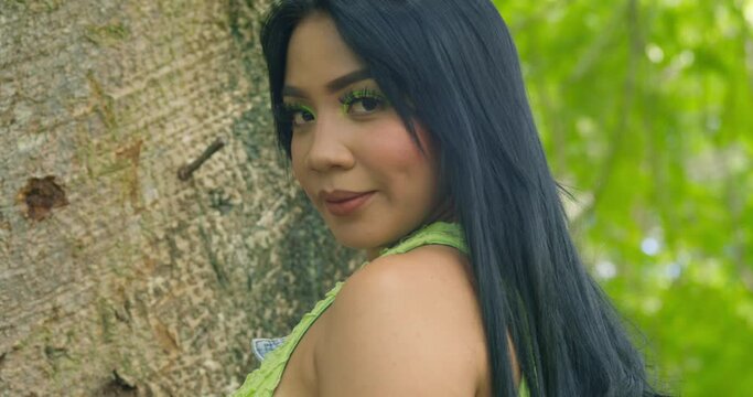 Facial close up of latin woman standing next to a large tree trunk on a Caribbean island
