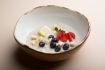 Bowl of oatmeal porridge served with strawberries and blueberries