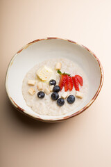 Bowl of oatmeal porridge served with strawberries and blueberries