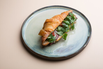 Fresh croissant stuffed with sliced ham and herbs