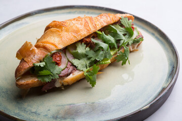 Fresh croissant stuffed with sliced ham and herbs