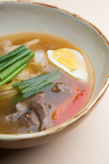 Bowl of hot beef noodle soup served with egg