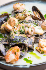 Plate of black seafood pasta with shrimps, mussels, squid