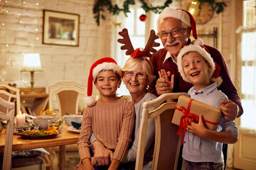 Happy grandparents with grandkids celebrate Christmas at home and look at camera.