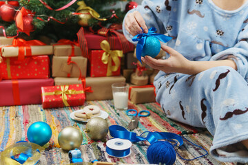 Cropped image of woman in pajamas decorating christmas tree with baubles at home