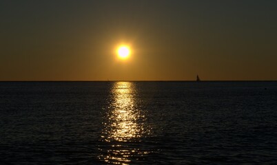 Naklejka na ściany i meble Sunset on the sea, sailboat on the horizon