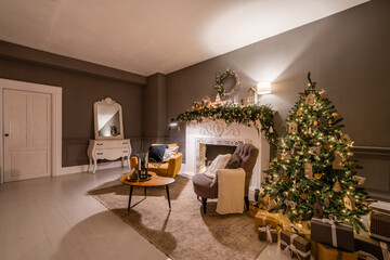Classic apartments with decorated christmas tree and presents. Christmas evening in the light of candles and garlands. Living with fireplace and stucco.