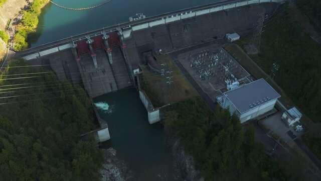 Aerial view of Mazegawa Dam, Tilt reveal at sunrise to mountains of Gifu, Japan