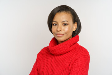 Portrait of confident woman wearing red knitted pullover. Happy african american female dressed in cozy woolen sweater isolated over gray wall. Studio shot of black millennial girl in warm clothes