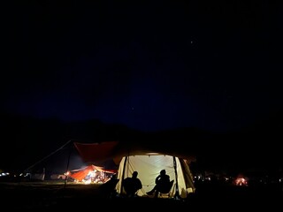 夜のテントの前で語らう男女のシルエット