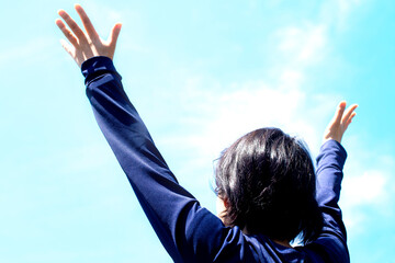 大空の下で若い女性が手を広げて見上げている
