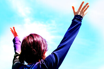 大空の下で若い女性が手を広げて見上げている