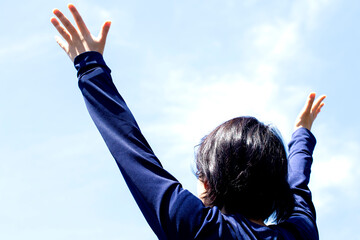 大空の下で若い女性が手を広げて見上げている