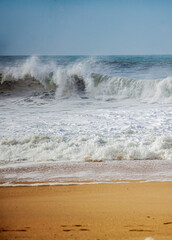 Beautiful ocean landscape. Wave breaking with splashes and foam on the sandy beach. Tropical Beach Vacation concept