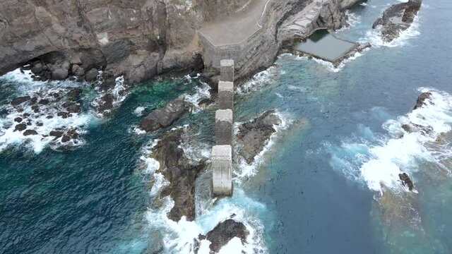 Top view of natural pools by the ocean with waves crashing on rocks in Pescante de Hermigua, La Gomera