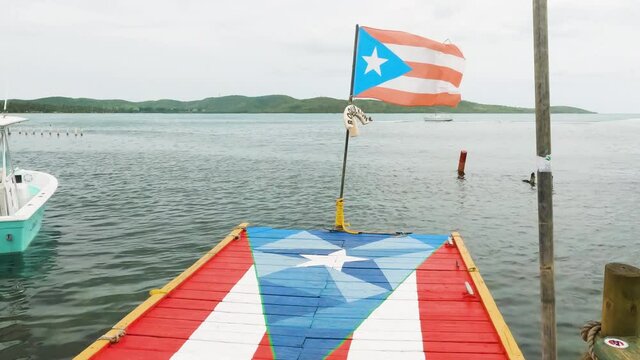 Pontoon painted with flag of Puerto Rico as national flag flaps in wind. Tilt upward shot.