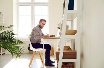 Serious focused businessman working on important work project in his bright home office. Side view...