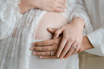 Close up of a cute pregnant belly.Cropped image of beautiful pregnant woman and her handsome husband hugging the tummy