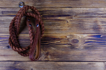 Brown leather dog leash on a wooden background. Top view