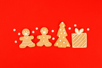 Happy New Year's 2022 set of gingerbread man in face mask from ginger biscuits glazed sugar icing decoration on classic traditional red background, minimal seasonal pandemic winter holiday banner