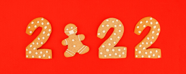 Happy New Year's, Christmas set of numbers 2022, gingerbread man in face mask from ginger biscuits glazed sugar icing decoration on red background, seasonal pandemic winter holiday banner