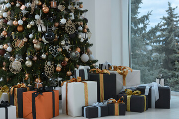 Many boxes with gifts near the Christmas tree.Christmas toys, decorations, gift boxes are decorated in black, white, orange, gold colors