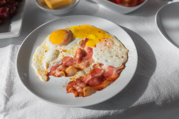 fried eggs with strips of juicy and fatty bacon on a plate during breakfast in a cafe or at home
