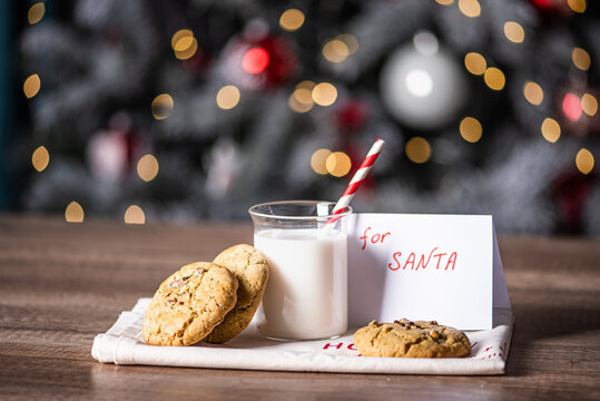 christmas cookies with a glass of milk and a letter for santa on background of blurred lights