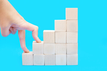 Hand climbing the stairs made of wooden blocks