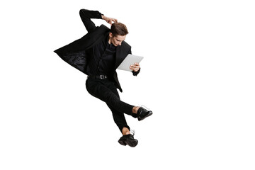 Young man in black business suit using tablet isolated on white background. Art, motion, action, flexibility, inspiration concept.