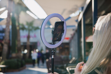 Young influencer in front of the camera and selfie ring light reading a text . SMM manager.